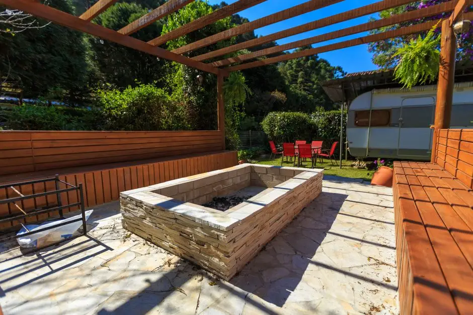 Paver patio with a fire pit and pergola in a wooded backyard